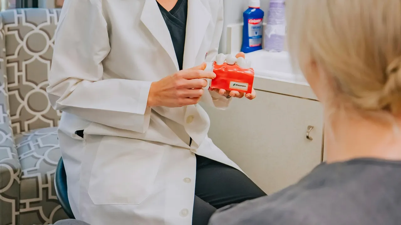Una dottoressa di Aurum Dentis mostra un modello dentale a una paziente