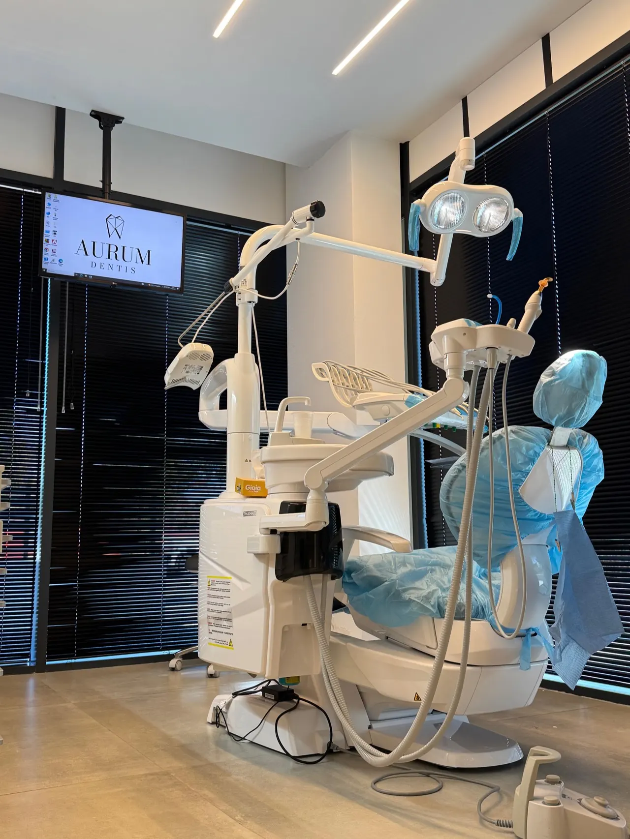 La sala odontoiatrica di Aurum Dentis: riunito preparato e monitor con il logo dello studio